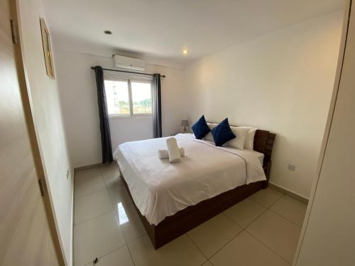 een slaapkamer met een groot wit bed met blauwe kussens bij Hovah Luxury Homes' 2BR Apartment in Accra