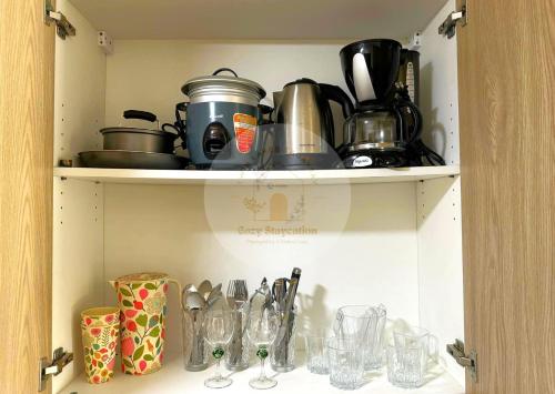 a cupboard filled with glasses and pots and pans at Twin Lakes Tagaytay - Cozy Staycation with Sglobal in Laurel