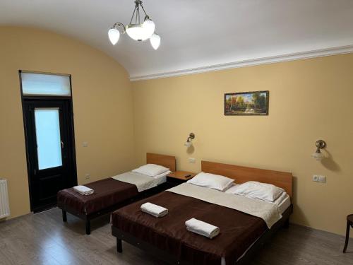 two beds in a room with yellow walls at TsisaR Bankir Hotel in Lviv