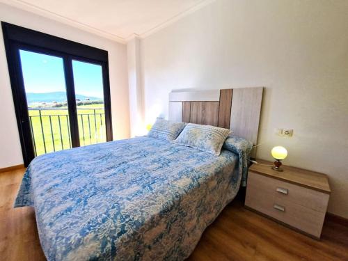 um quarto com uma cama e uma grande janela em Apartamento Playa Foz em Foz