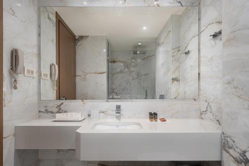 a white bathroom with a sink and a mirror at Civitel Akali Hotel in Chania