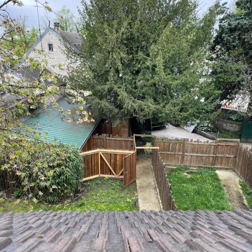 une arrière-cour avec une clôture en bois et un arbre dans l'établissement Maison Le Clos des Cerfs by La Boîte En Plus, à Senlis