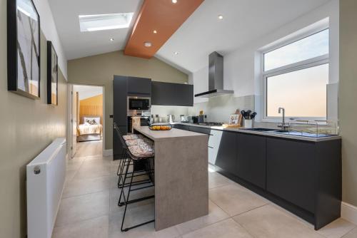 a kitchen with black cabinets and a large window at 4-BR Chic Spacious House with Parking, Central Bolton, Links to Manchester, Sleeps - 11 by Blue Puffin Stays in Farnworth