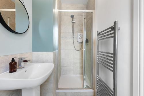 a bathroom with a shower and a sink and a mirror at 4-Bedroom Stunning Luxe, Spacious & Stylish Design House Bolton, Sleeps 11, with Parking Central Bolton, Links to Manchester, Pet-Friendly, Best For Groups! WORK CONTRACTORS SPECIAL OFFER! - by Blue Puffin Stays in Farnworth