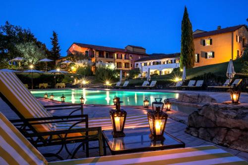 un complejo con piscina por la noche en La Meridiana Hotel & Golf Resort, en Garlenda