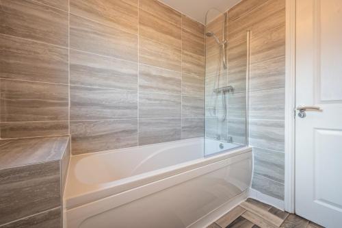 a bathroom with a white tub and a shower at Atlanta's Residence by Tŷ SA in Newport