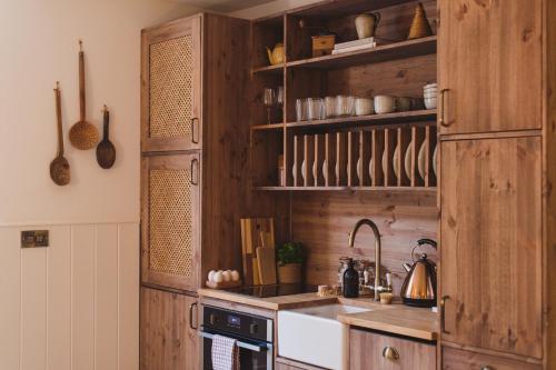 eine Küche mit Holzschränken und einer Spüle in der Unterkunft Buckingham Mews Pebble Cottage 3 in Broadstairs
