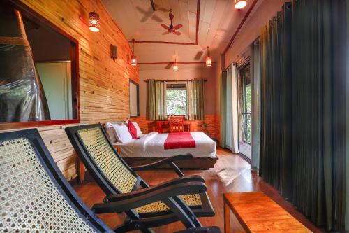 a bedroom with a bed and chairs in a room at Vythiri Resort in Vythiri