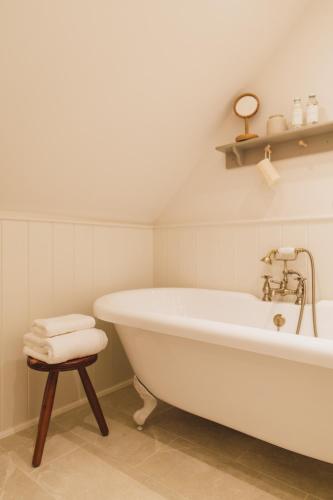 a white bath tub in a bathroom with a stool at Buckingham Mews Pebble Cottage 3 in Broadstairs