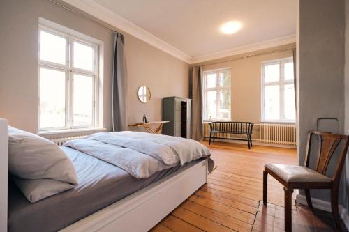 Schlafzimmer mit einem Bett, einem Stuhl und Fenstern in der Unterkunft Villa Rosa Charmante Altbauwohnung in Flensburg in Flensburg