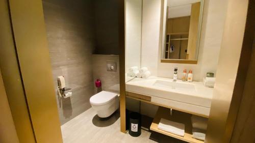 a bathroom with a toilet and a sink and a mirror at Crowne Plaza Fuzhou South by IHG in Fuzhou