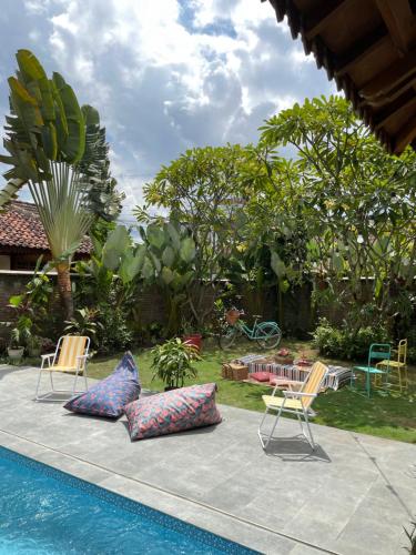 una piscina con 2 sillas y almohadas en un patio en Summergrass B&B, en Yogyakarta