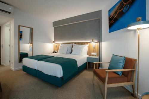 um quarto com uma cama grande e uma cadeira em Rochavau Hotel em Portimão