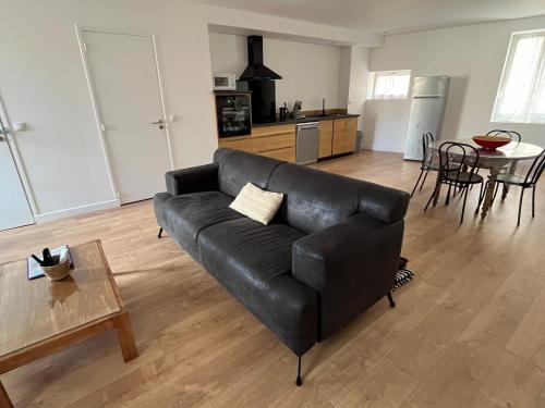 un salon avec un canapé noir et une table dans l'établissement Maison rénovée entre coeur de village et garrigue, à Saint-Martin-de-Londres