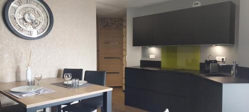 une cuisine avec une table et une horloge au mur dans l'établissement LE PANORAMIQUE, à Toulouse