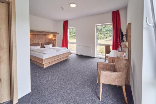 a bedroom with a bed and a desk and a chair at Hotel am Interpark in Großmehring