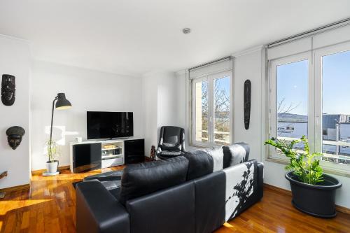 a living room with a black leather couch and a tv at Lisbon Riverview Apartment by Premium Lisbon Stays in Lisbon