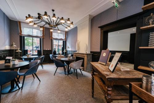 a restaurant with tables and chairs and a chandelier at Catalonia Vondel Amsterdam in Amsterdam