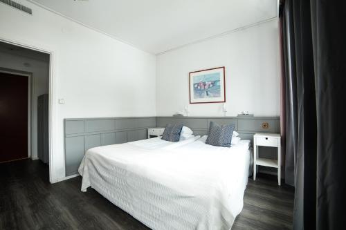 a bedroom with a white bed with blue pillows at Stadshotellet Lidköping in Lidköping