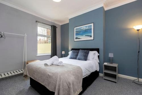 a bedroom with blue walls and a bed and a window at Comfortable & very spacious home in Stockton-on-Tees