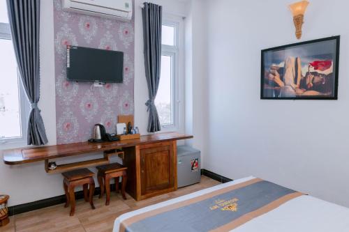 um quarto com uma secretária e uma televisão na parede em Hotel Hoàng My Phú Yên em Liên Trì (3)