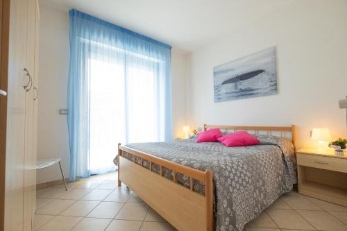 Schlafzimmer mit einem Bett mit rosa Kissen und einem Fenster in der Unterkunft Green Bay C12 - Pineto Vacanza in Pineto