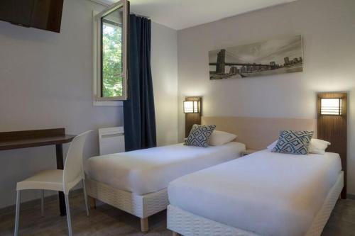 a room with two beds and a desk and a window at The Originals City, Hotel Novella Confort, Nantes Est in Carquefou