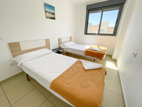um pequeno quarto com 2 camas e uma janela em Apartamentos Benicarló Lowcost 3000 em Benicarló