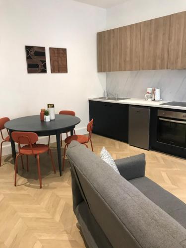 un salon avec un canapé et une table et une cuisine dans l'établissement Joli appartement en Maison de Ville, à Valréas