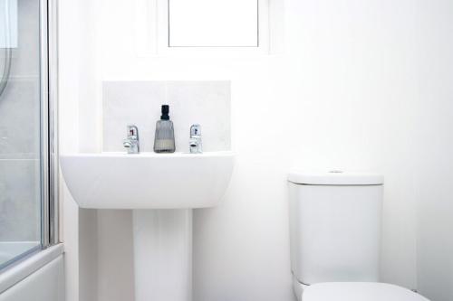 Baño blanco con lavabo y aseo en Buxton Way by Tŷ SA - 3 bedroom house, en Royal Wootton Bassett