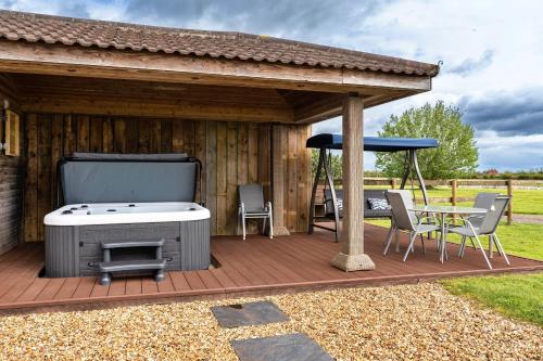 a wooden deck with a grill and a table and umbrella at Finest Retreats - Stone Bow Farmhouse in Weston-super-Mare