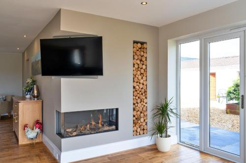 a living room with a fireplace and a flat screen tv at Finest Retreats - Stone Bow Farmhouse in Weston-super-Mare