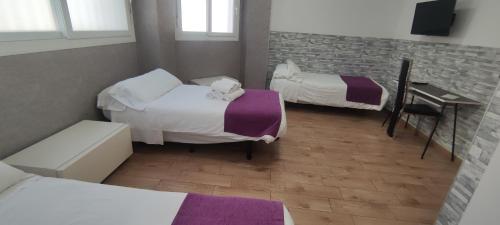 a room with two beds and a desk with a desk at Habitaciones El Escorial in Majadahonda