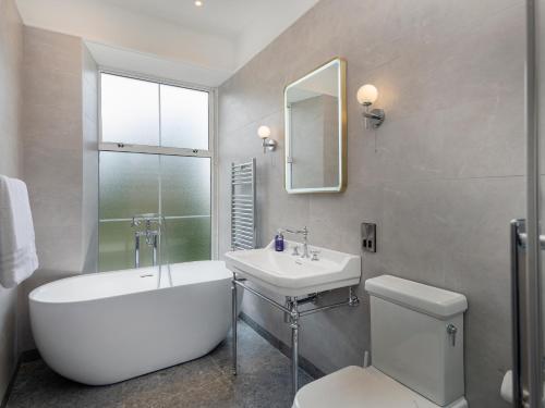 a bathroom with a tub and a sink and a toilet at Castle Oaks House Hotel in Limerick