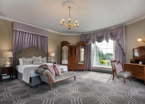 a bedroom with a bed and a chair and a chandelier at Castle Oaks House Hotel in Limerick