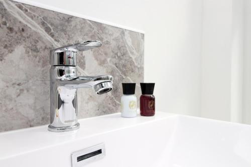 a bathroom sink with a faucet and two bottles of soap at Modern 1 Bedroom - Caxton Place by Tŷ SA in Newport