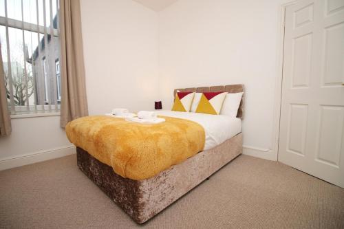 a bedroom with a bed with a yellow blanket at Camelot House by Tŷ SA in Newport