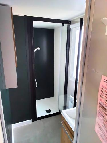 une salle de bain avec une porte noire et blanche avec un miroir dans l'établissement CAMPING SIBLU - LA RESERVE **** - Mobile Home - 3 ch. - (8pers), à Gastes