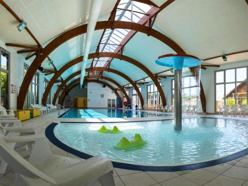 une grande piscine intérieure avec des chaises et un toboggan aquatique dans l'établissement CAMPING SIBLU - LA RESERVE **** - Mobile Home - 3 ch. - (8pers), à Gastes