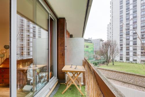 a balcony with a wooden table and a window at T2 lumineux avec terrasse in Boulogne-Billancourt