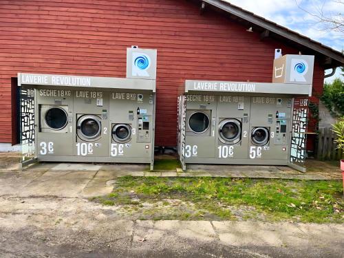 duas máquinas de lavar roupa em frente a um edifício vermelho em CAMPING SIBLU - LA RESERVE **** - Mobile Home - 3 ch. - (8pers) em Gastes