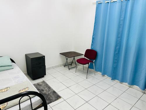 シャルジャにあるBoys accommodationのテーブル、椅子2脚、青いカーテンが備わる客室です。