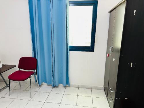 シャルジャにあるBoys accommodationの赤い椅子と窓が備わる客室です。