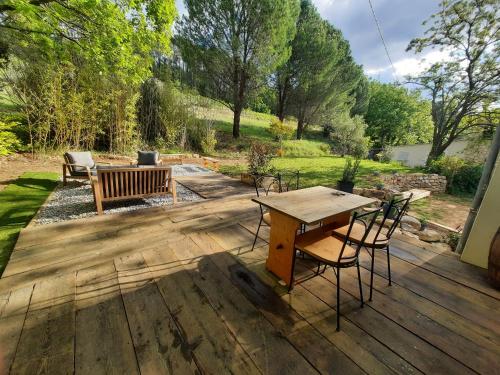 a wooden deck with a table and chairs on it at La Figueraie in Vinezac