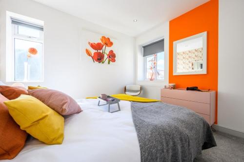 a bedroom with a bed with an orange wall at Central Location - Riverside Gardens #2 by Tŷ SA in Cardiff
