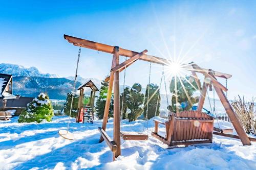 a swing in the snow with the sun shining at Górski Pałacyk Kompleks obiektów in Kościelisko