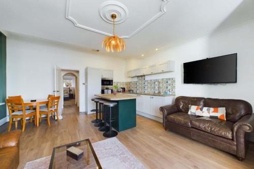 sala de estar y cocina con sofá y mesa en Loveliest Homes Torquay - 3 bed, 2 bathroom, balcony, parking en Torquay