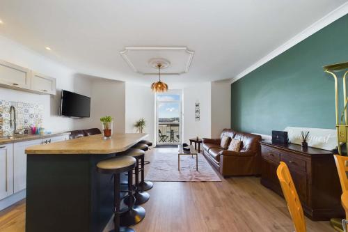 a kitchen and living room with a bar and a couch at Loveliest Homes Torquay - 3 bed, 2 bathroom, balcony, parking in Torquay