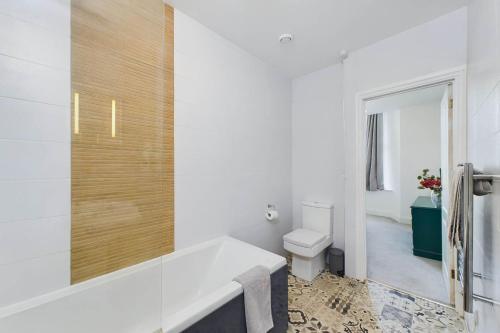 a white bathroom with a tub and a toilet at Loveliest Homes Torquay - 3 bed, 2 bathroom, balcony, parking in Torquay