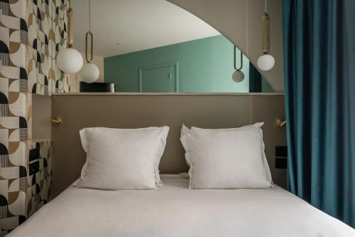 1 cama con 2 almohadas blancas en una habitación en Arc Elysées, en París